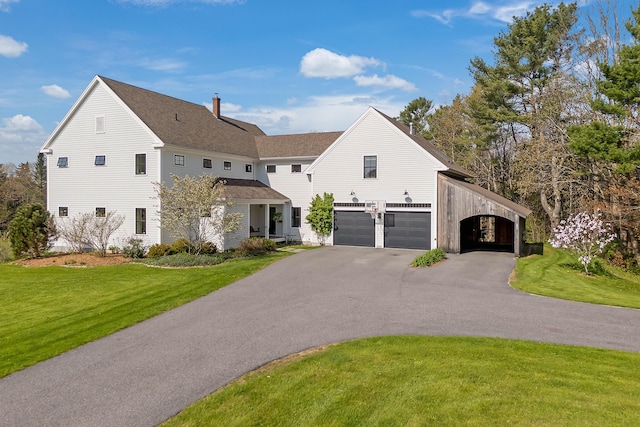 view of front of property featuring a front lawn, a chimney, asphalt driveway, an attached garage, and a shingled roof