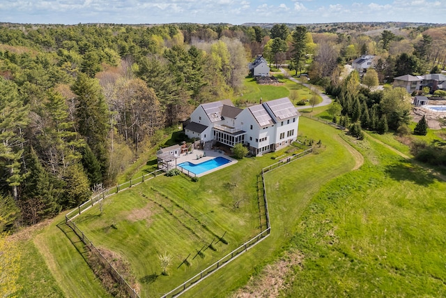 aerial view of property and surrounding area featuring a pool area and a forest