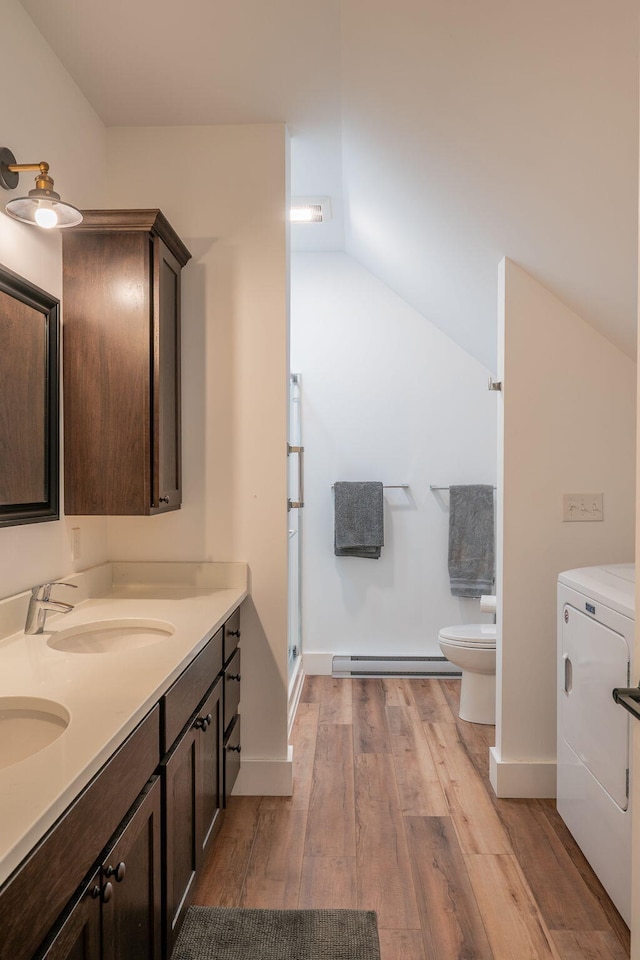 bathroom featuring washer / dryer, a baseboard radiator, vaulted ceiling, toilet, and wood finished floors