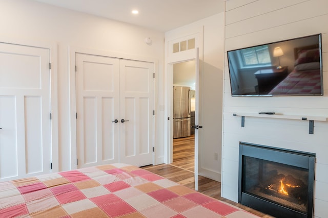 unfurnished bedroom featuring light wood-style flooring, a closet, recessed lighting, and a glass covered fireplace