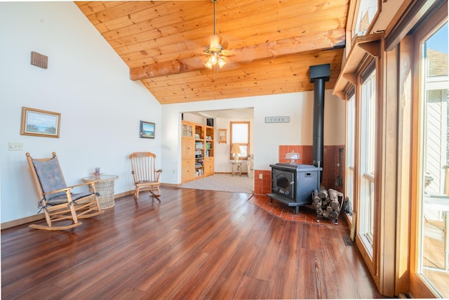 living area featuring vaulted ceiling, a wood stove, dark hardwood / wood-style flooring, ceiling fan, and wood ceiling