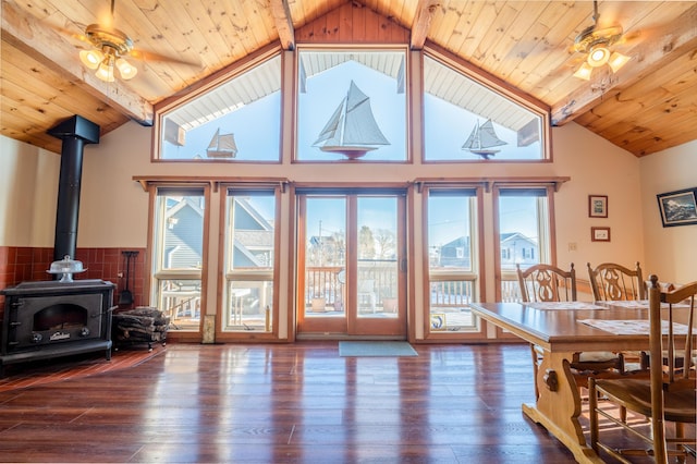 dining space featuring beamed ceiling, a wood stove, wood ceiling, and dark hardwood / wood-style flooring