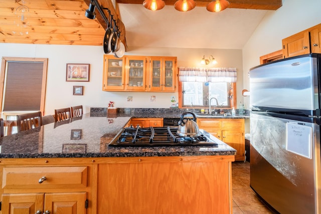 kitchen with lofted ceiling, sink, stainless steel fridge, a kitchen breakfast bar, and black gas cooktop