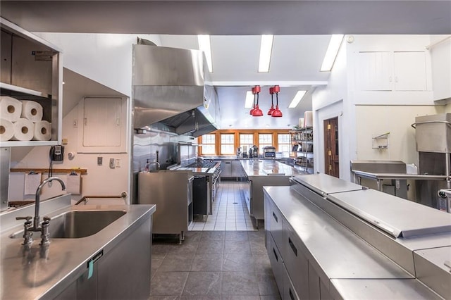 kitchen featuring sink, decorative light fixtures, vaulted ceiling, dark tile patterned flooring, and island range hood