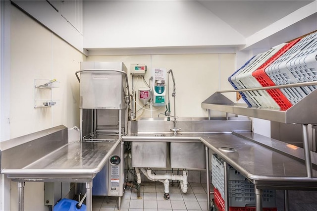 kitchen featuring lofted ceiling, tile patterned floors, and stainless steel counters