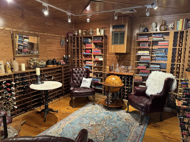 wine area with wood ceiling, track lighting, wood walls, and hardwood / wood-style flooring