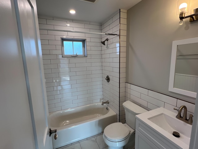 full bathroom with toilet, tile patterned floors, vanity, tile walls, and tiled shower / bath