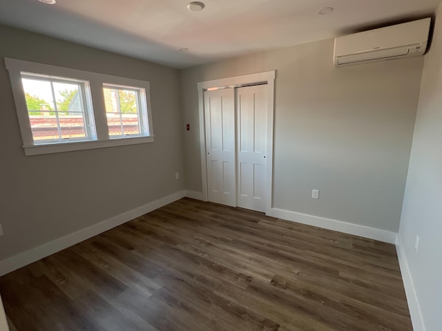 unfurnished bedroom featuring dark hardwood / wood-style flooring, a wall unit AC, and a closet