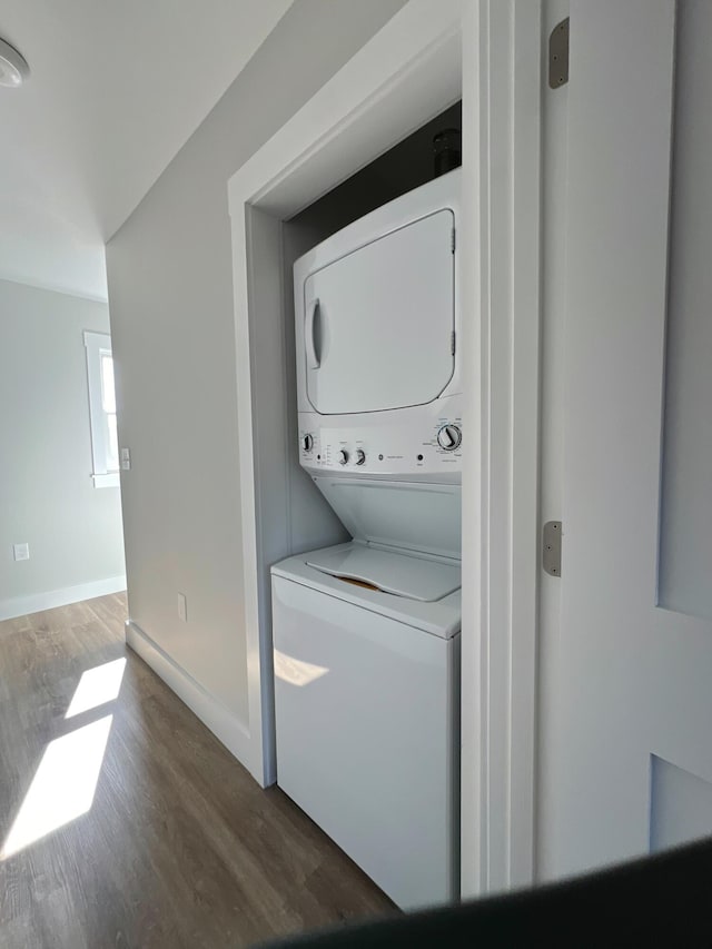 washroom featuring dark wood-type flooring and stacked washer / dryer