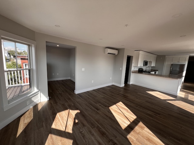 unfurnished living room with an AC wall unit and dark hardwood / wood-style flooring