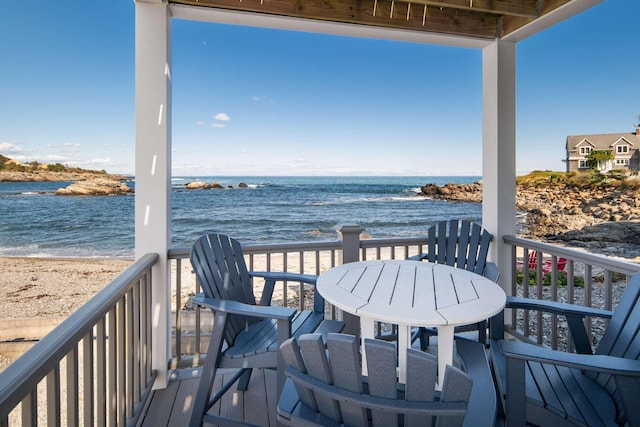 wooden deck featuring a beach view and a water view