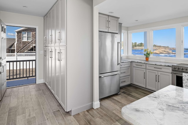 kitchen with appliances with stainless steel finishes, a water view, gray cabinets, and light stone countertops