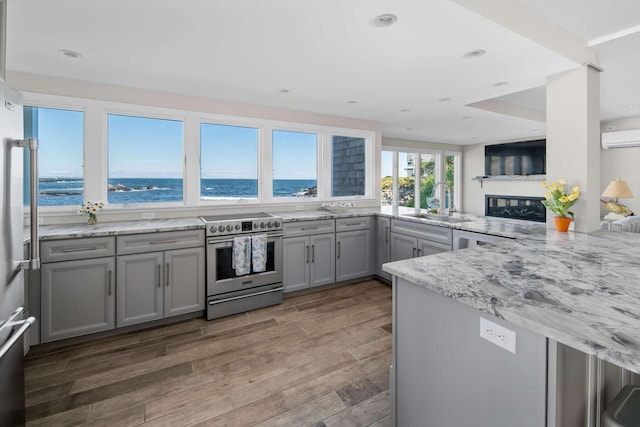 kitchen featuring electric stove, gray cabinets, wood-type flooring, a water view, and kitchen peninsula