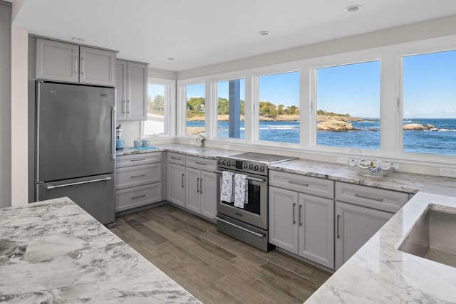 kitchen featuring dark hardwood / wood-style flooring, a water view, gray cabinetry, and appliances with stainless steel finishes