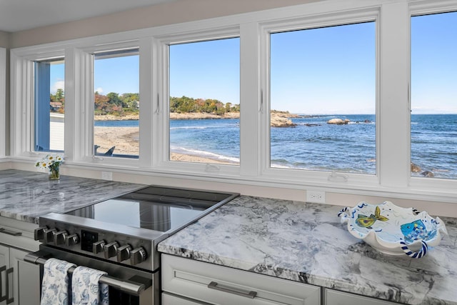 kitchen with stainless steel electric range oven, white cabinetry, a water view, and light stone countertops