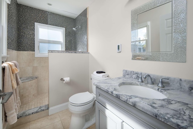 bathroom featuring a tile shower, vanity, tile patterned flooring, and a healthy amount of sunlight