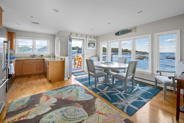 dining area with a healthy amount of sunlight, light hardwood / wood-style flooring, and a water view