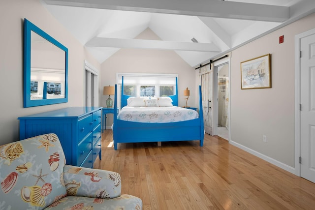 bedroom featuring a barn door, lofted ceiling with beams, and light hardwood / wood-style floors