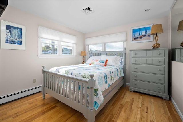 bedroom with light hardwood / wood-style floors, multiple windows, and a baseboard heating unit