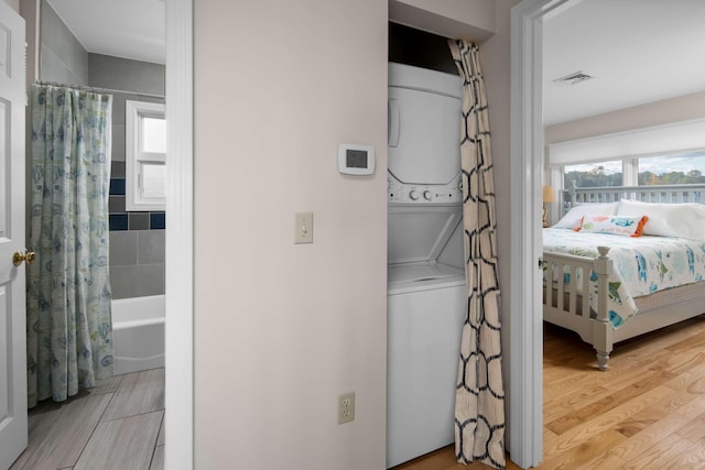 washroom with light wood-type flooring and stacked washer / drying machine