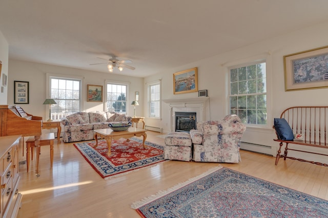 living room with ceiling fan, baseboard heating, and light hardwood / wood-style flooring