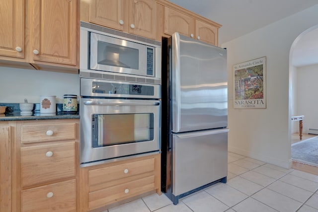 kitchen featuring light brown cabinetry, light tile patterned flooring, stainless steel appliances, and a baseboard radiator