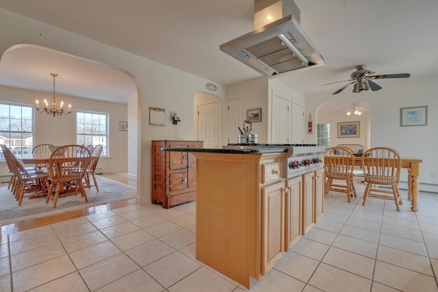 kitchen with ceiling fan with notable chandelier, a kitchen island, decorative light fixtures, island range hood, and light tile patterned floors