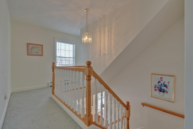 hallway with baseboard heating, light carpet, and a chandelier