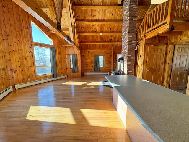 kitchen with light wood-type flooring, a baseboard heating unit, beamed ceiling, and wooden walls