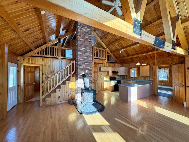 interior space with high vaulted ceiling, a wood stove, and wood walls