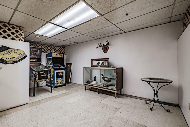 basement with a paneled ceiling and refrigerator