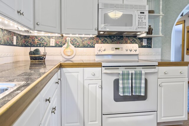 kitchen with white appliances, white cabinets, and backsplash