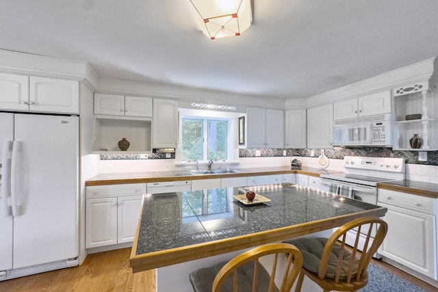 kitchen featuring sink, white cabinets, a center island, white appliances, and a kitchen breakfast bar