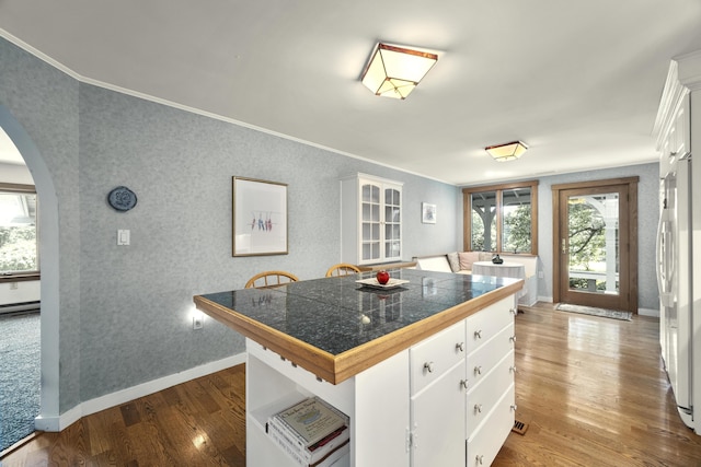 kitchen with white fridge, crown molding, a breakfast bar, dark hardwood / wood-style floors, and white cabinetry