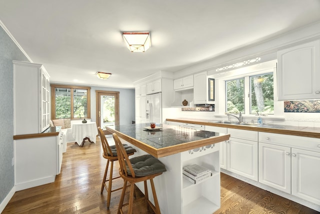 kitchen with sink, white cabinets, a kitchen breakfast bar, dark hardwood / wood-style flooring, and white fridge with ice dispenser