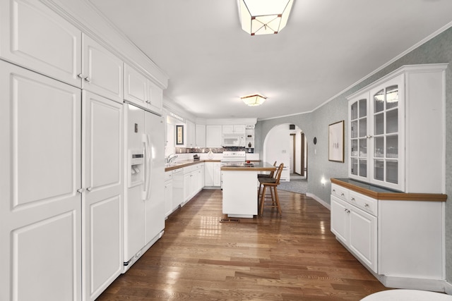 kitchen with a kitchen island, a kitchen breakfast bar, white appliances, and white cabinetry