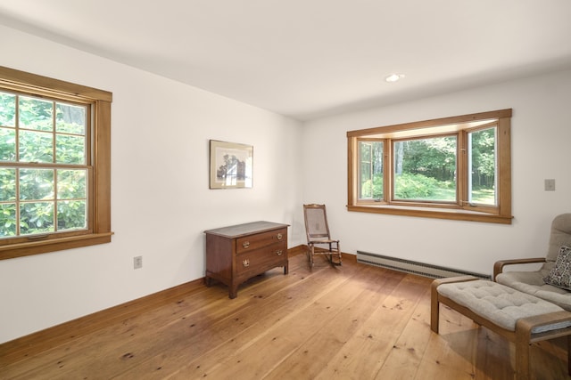 living area featuring a baseboard heating unit, light wood-type flooring, and plenty of natural light