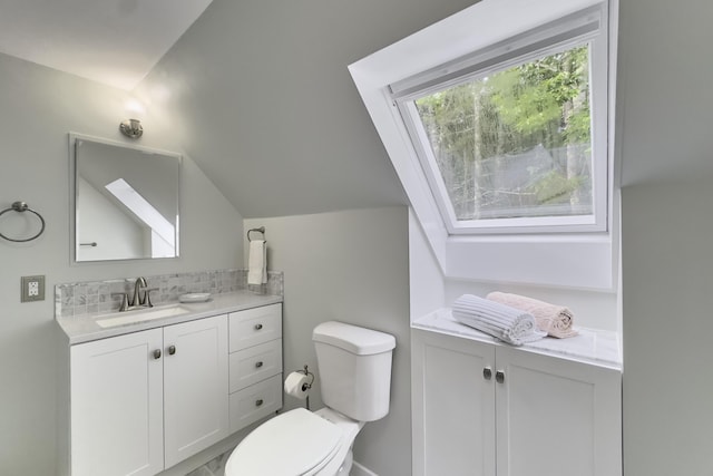 bathroom with tasteful backsplash, lofted ceiling, vanity, and toilet