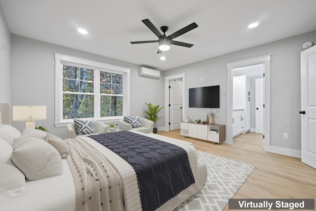 bedroom featuring ensuite bathroom, an AC wall unit, ceiling fan, and light wood-type flooring