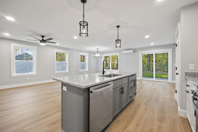 kitchen featuring appliances with stainless steel finishes, an island with sink, ceiling fan, sink, and decorative light fixtures