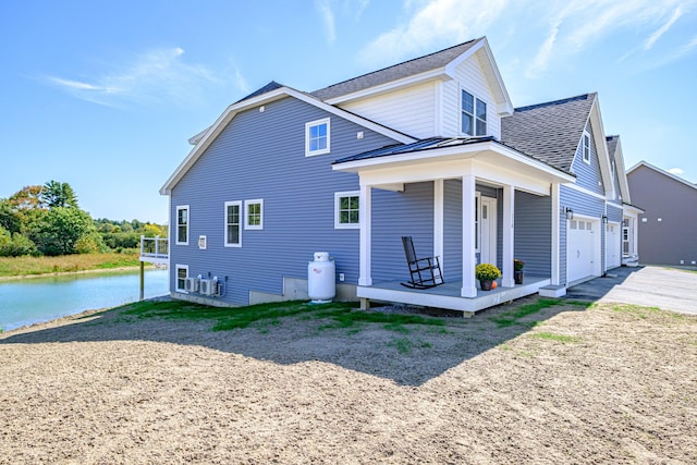 exterior space with a water view, a garage, and covered porch