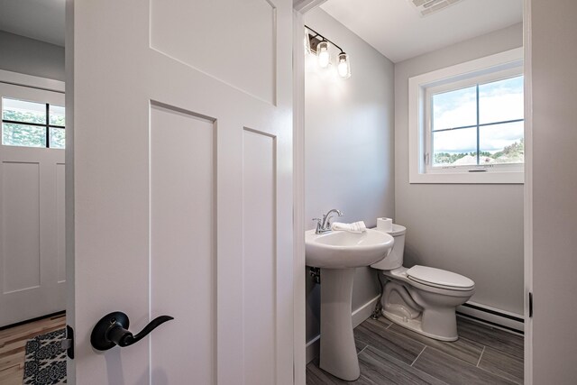 bathroom featuring toilet, baseboard heating, and sink