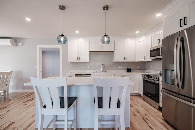 kitchen with decorative light fixtures, white cabinets, a kitchen breakfast bar, a wall unit AC, and appliances with stainless steel finishes