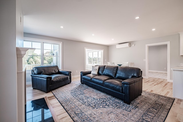 living room featuring light wood-type flooring, a healthy amount of sunlight, and a wall mounted AC