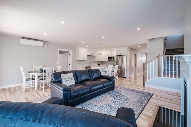 living room with an AC wall unit and light hardwood / wood-style floors