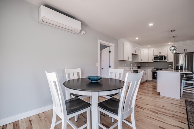 dining space with sink, light hardwood / wood-style floors, and an AC wall unit