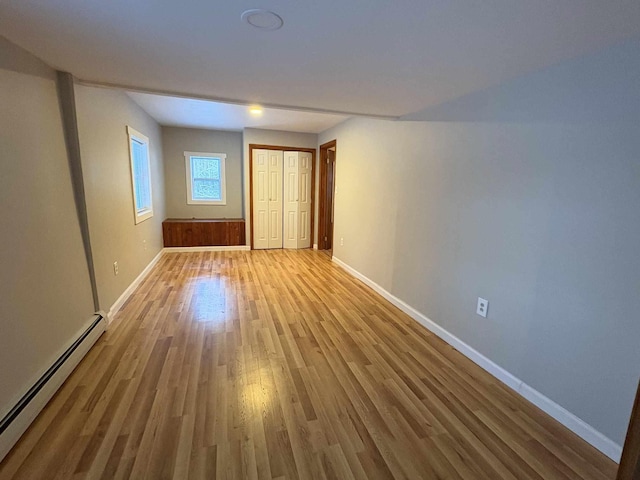 empty room featuring baseboard heating and hardwood / wood-style flooring