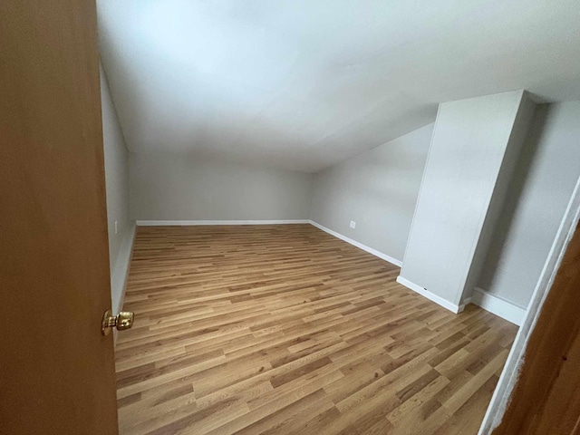 bonus room featuring light wood-type flooring and vaulted ceiling