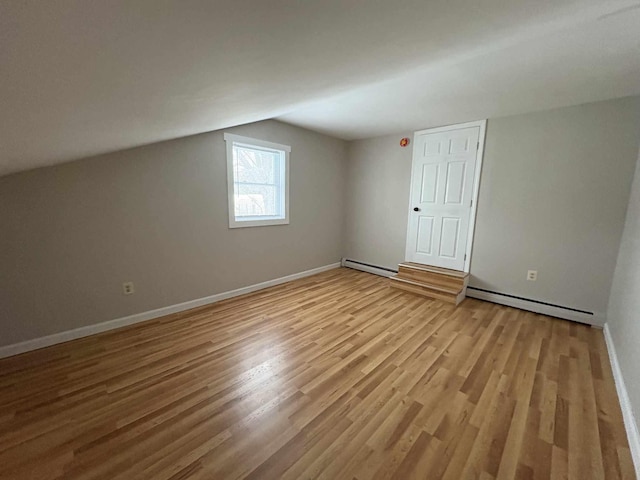 bonus room featuring light hardwood / wood-style flooring, lofted ceiling, and a baseboard heating unit