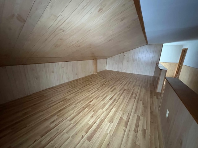 additional living space featuring lofted ceiling, wooden ceiling, wood walls, and light hardwood / wood-style flooring